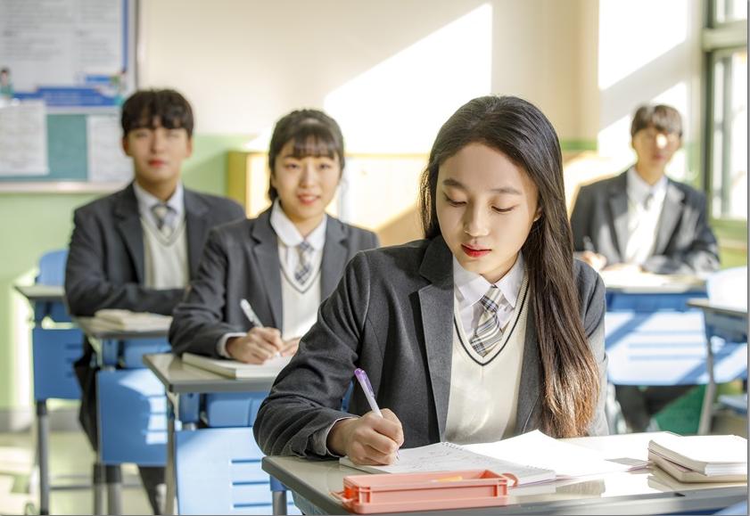 교실 책상에서 필기하는 학생