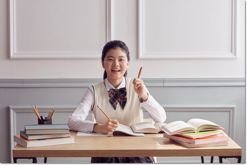책상 앞에서 손을 들고 질문하는 학생