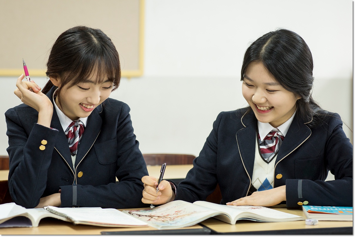 교실에서 함께 교재를 확인하는 두 학생