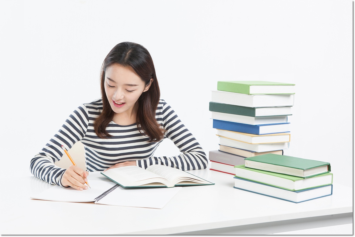 쌓인 책 옆에서 공부하는 학생