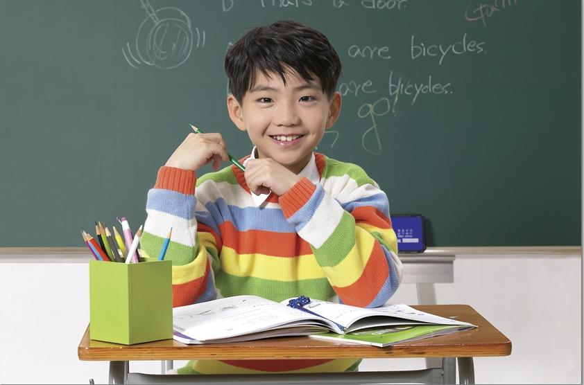 책상 앞에서 웃으며 손을 든 학생