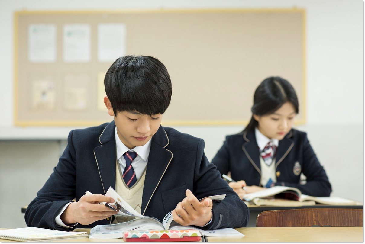교실 책상에서 학습지에 적는 학생