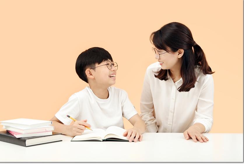 학생과 교재를 보며 대화하는 어른