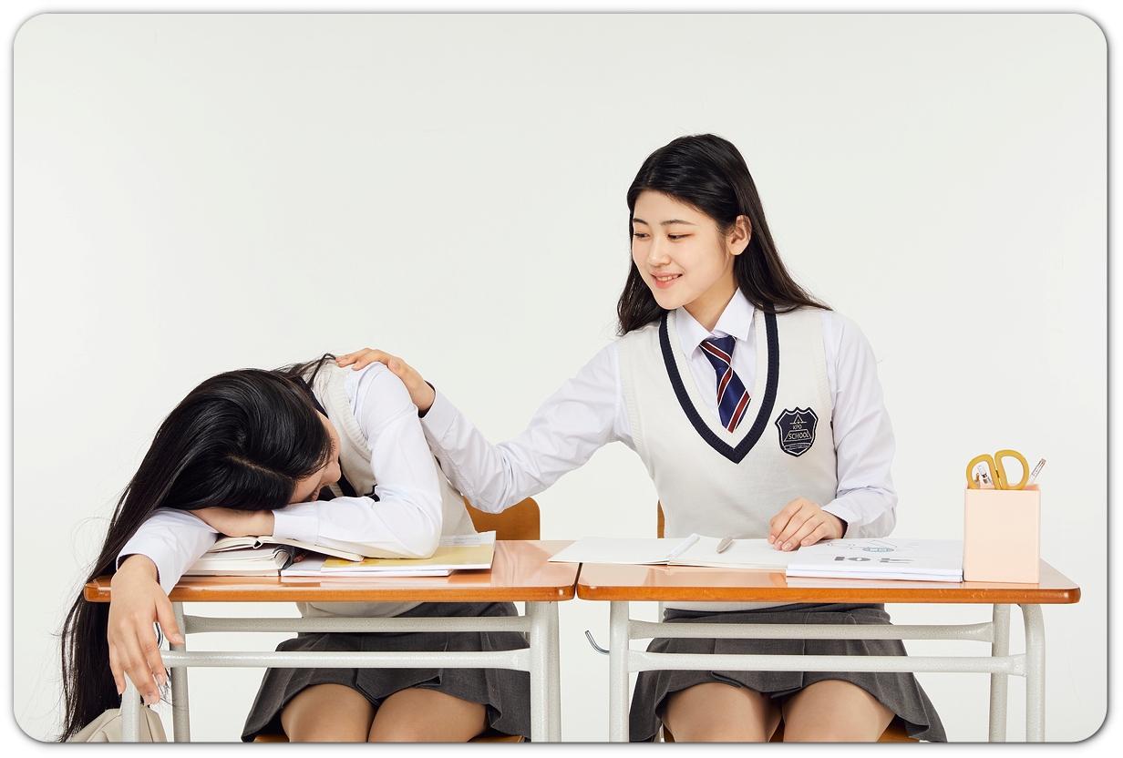 책상에서 쉬는 학생과 옆에서 바라보는 학생