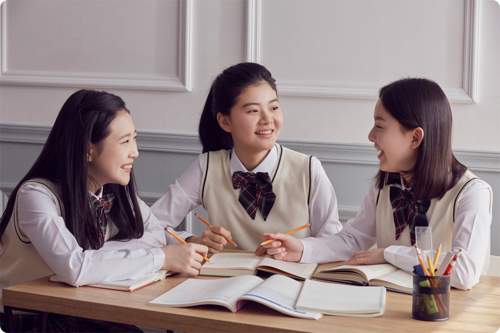 교재를 함께 보며 대화하는 세 학생