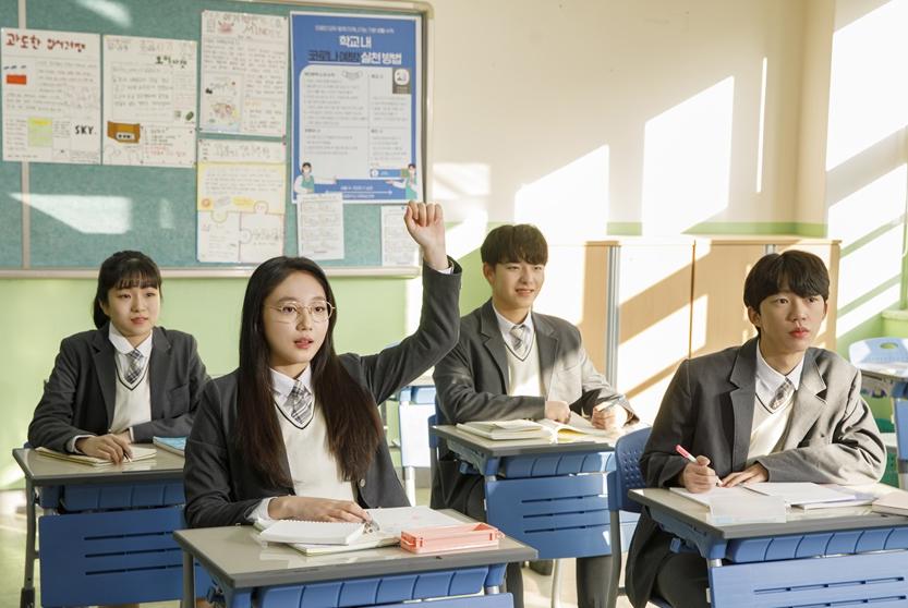 교실에서 손을 들어 질문하는 학생과 수업을 듣는 학생들