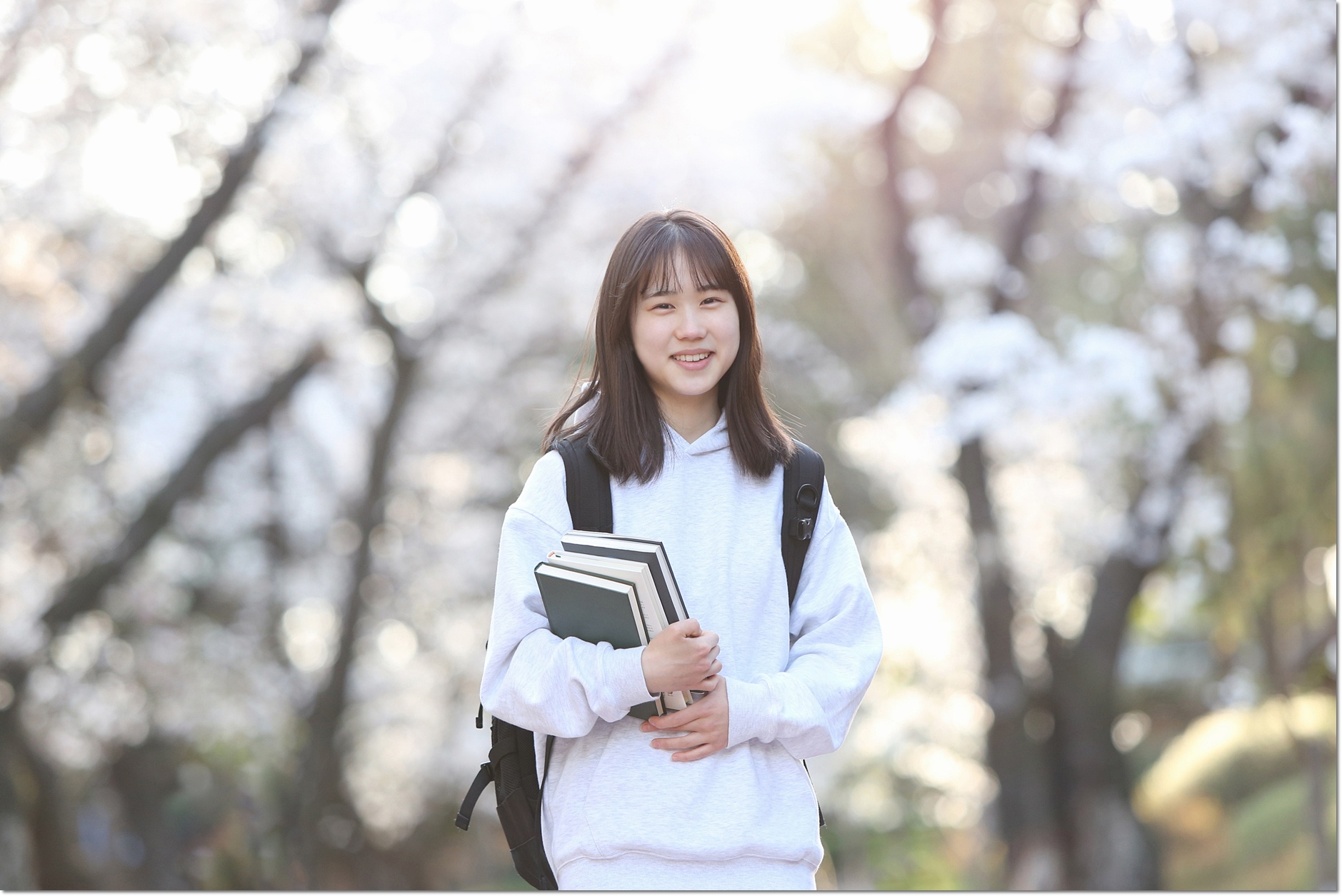 야외에서 책을 들고 서 있는 학생