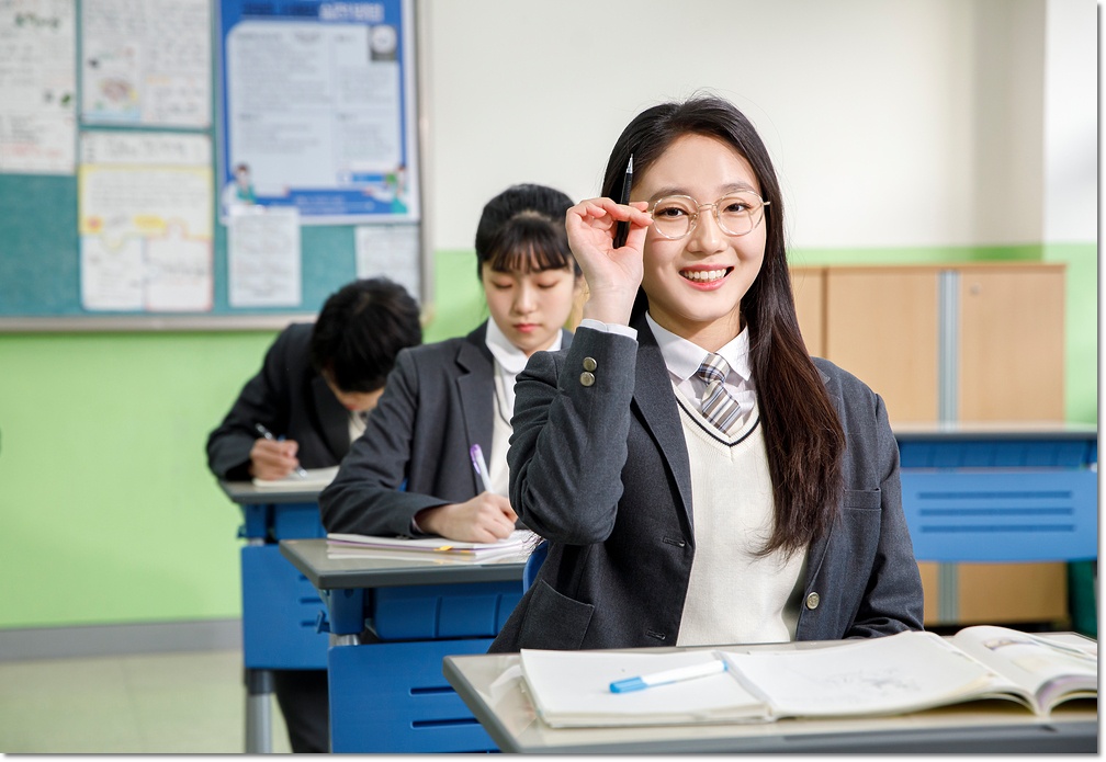 교실 책상에서 손을 들어 질문하는 학생