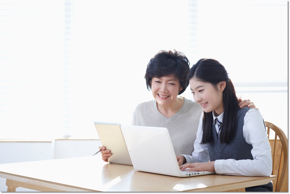 노트북 화면을 함께 확인하는 학생과 어른