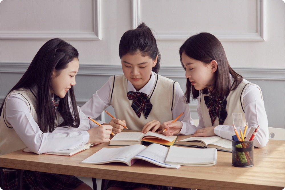 교재를 함께 보며 대화하는 세 학생
